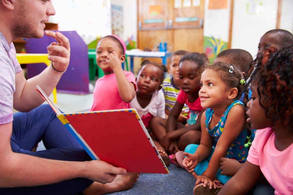 Volunteer teacher reading to a class of preschool kids